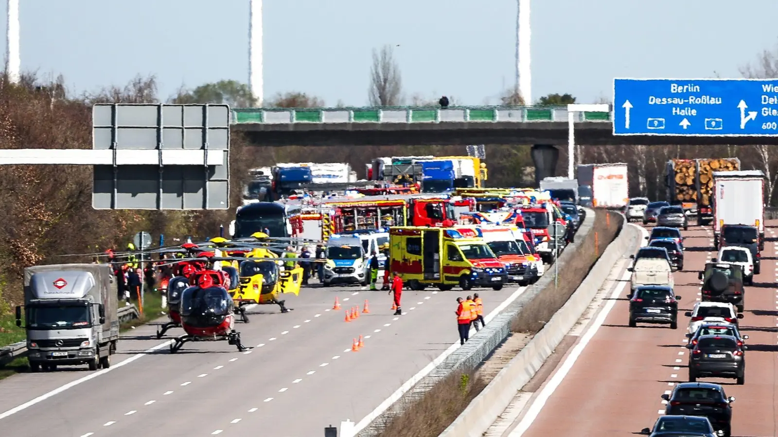 Einsatzfahrzeuge und Rettungshubschrauber stehen auf der A9 an der Unfallstelle. (Bild: Jan Woitas/dpa)