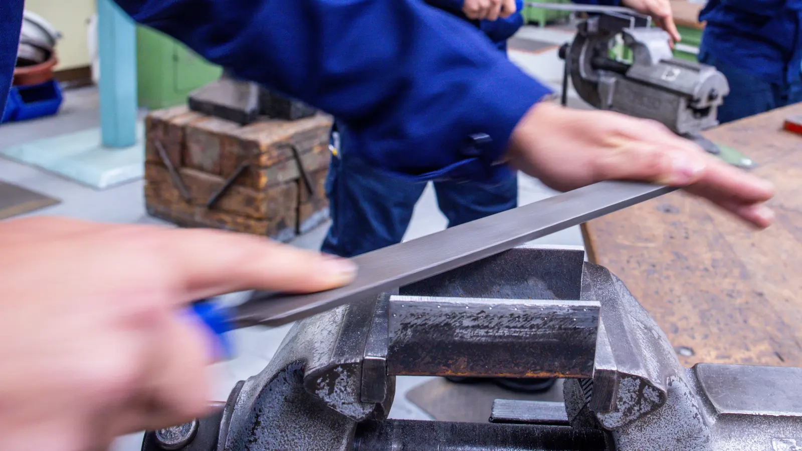 Lehrlinge arbeiten mit der Metallfeile an Schraubstöcken in einer Lehrwerkstatt.  (Symbolbild: Jens Büttner/dpa)