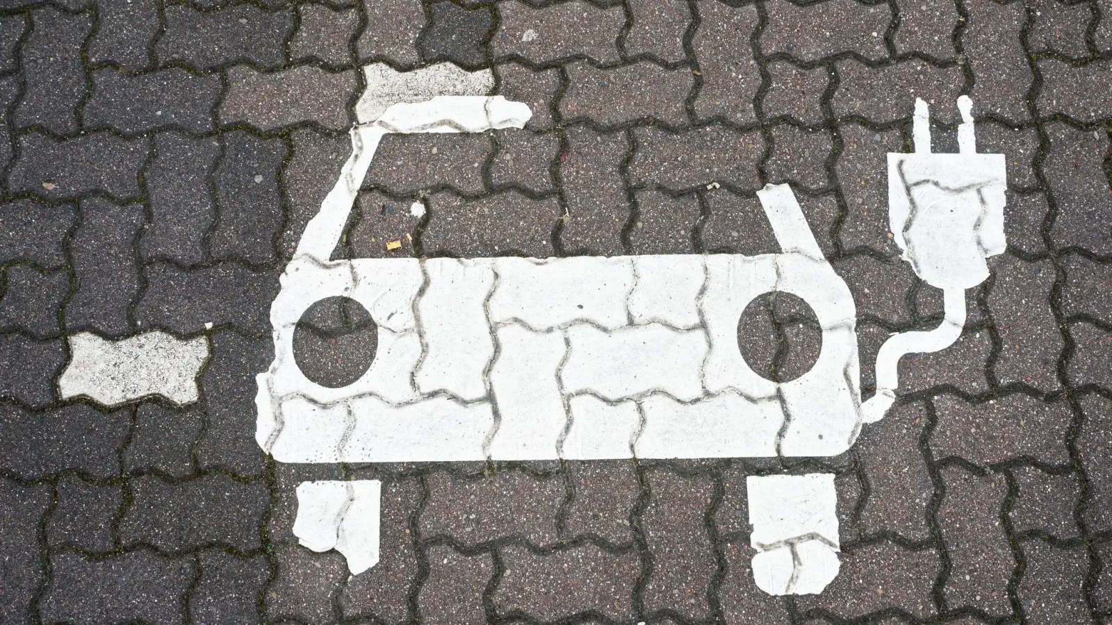 Ein Symbol für E-Autos ist auf einem Parkplatz zu sehen. (Symbolbild: Julian Stratenschulte/dpa/dpa-tmn)