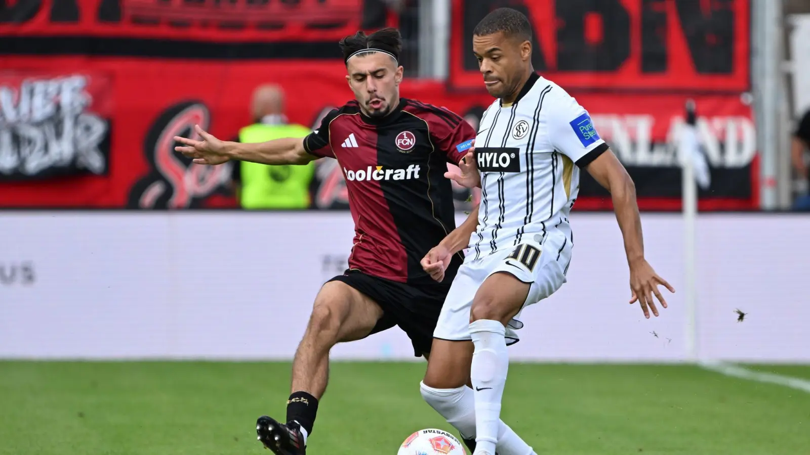 Die SV Elversberg um Jan Gyamerah (r) und der 1. FC Nürnberg um Berkay Yılmaz lieferten sich einen umkämpften Zweitliga-Auftakt. (Bild: Harald Tittel/dpa)