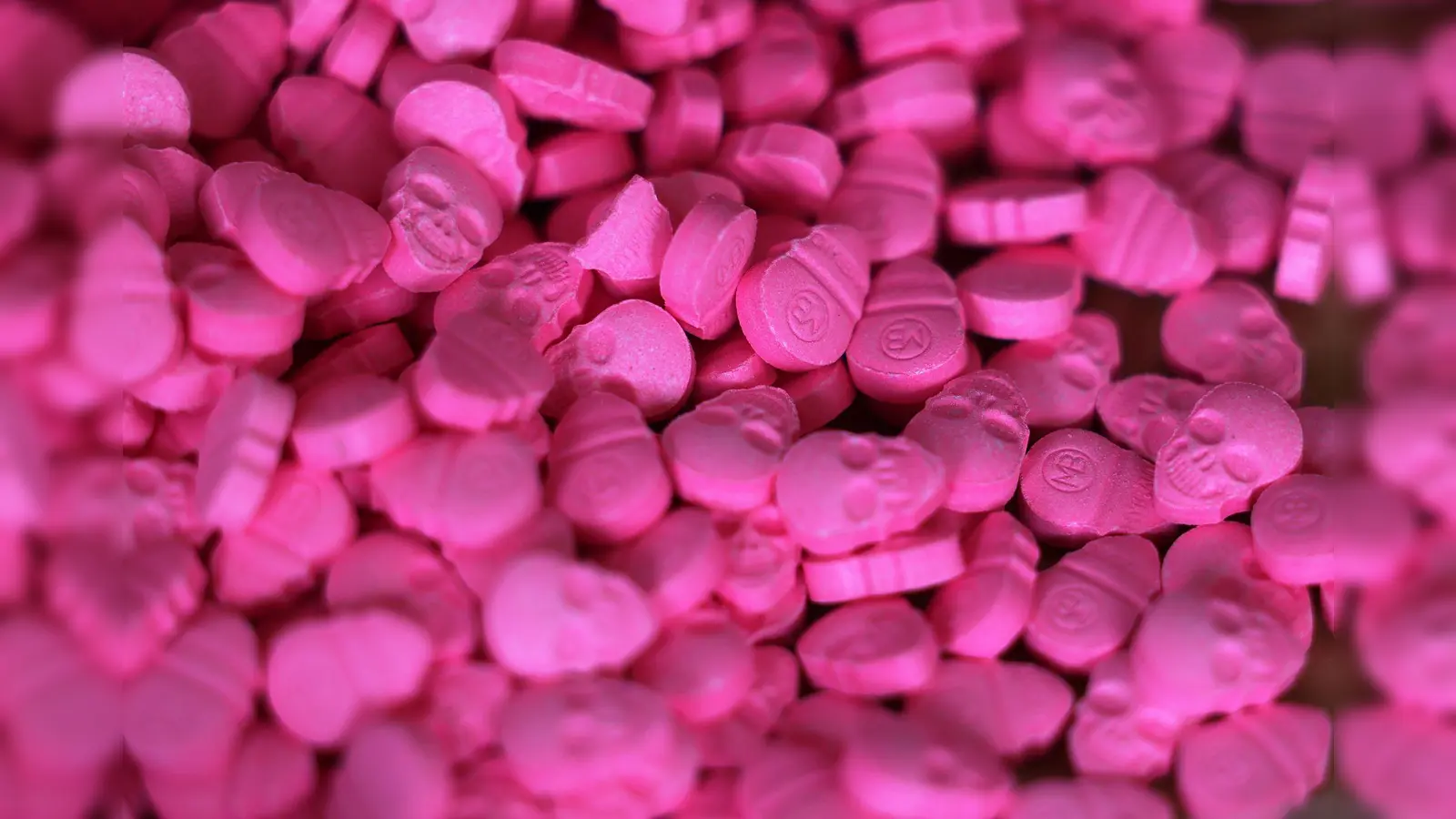 Ecstasy-Tabletten in Form von Totenköpfen liegen in einem Zollamt auf einem Tisch. Die Droge gibt es auch in flüssiger Form. (Symbolbild: Oliver Berg/dpa)