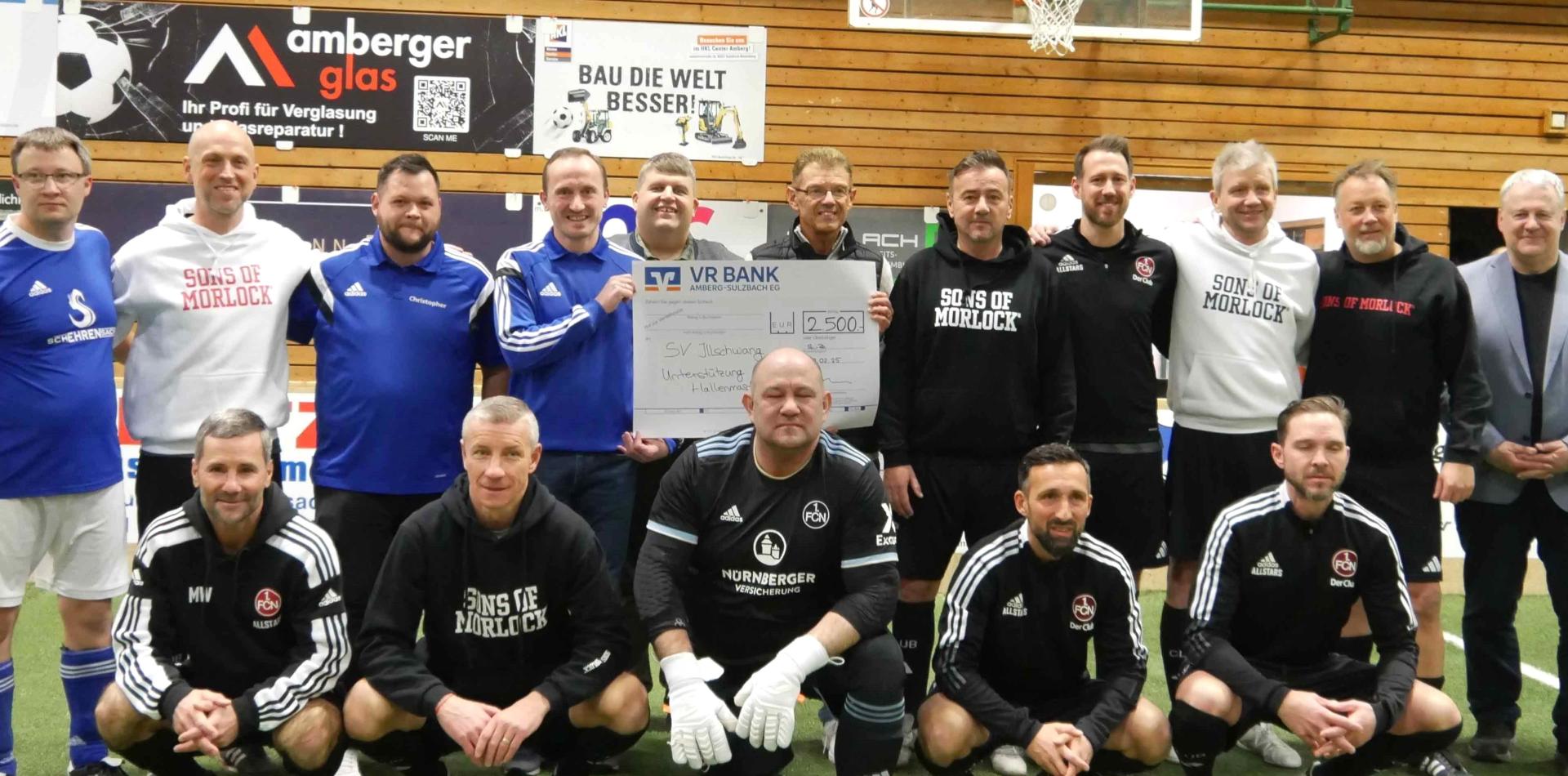 Die Traditionsmannschaft des 1. FC Nürnberg mit Teamchef Thomas Ziemer (stehend, Fünfter von rechts) und dem früheren Bundesliga-Torschützenkönig Marek Mintal (knieend, Zweiter von links) gesellt sich bei der Übergabe des 2500 Euro schweren Spendenschecks der VR-Bank an den SV Illschwang dazu. (Bild: no)