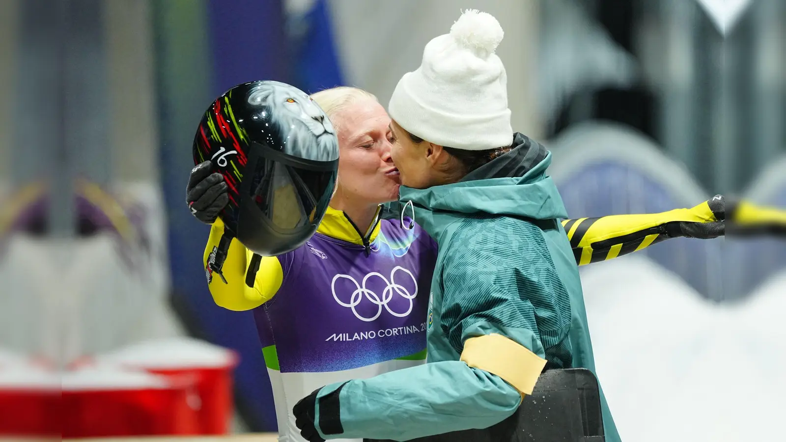 Die belgische Skeletonfahrerin Kim Meylemans (links) und ihre Frau Nicole Silveira, die für Brasilien antrat, küssen sich im Ziel. (Bild: Michael Kappeler/dpa)