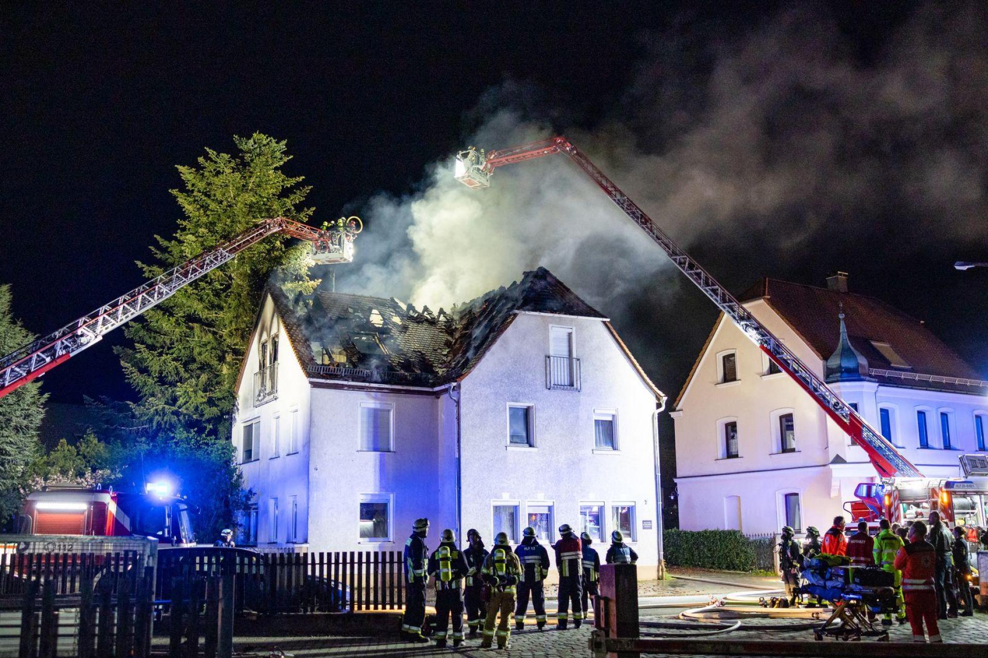 Einsatzkräfte der Feuerwehr sind mit einer Drehleiter am Brand eines Dachstuhls in Nürnberg beschäftigt. (Bild: David Oßwald/NEWS5/dpa)
