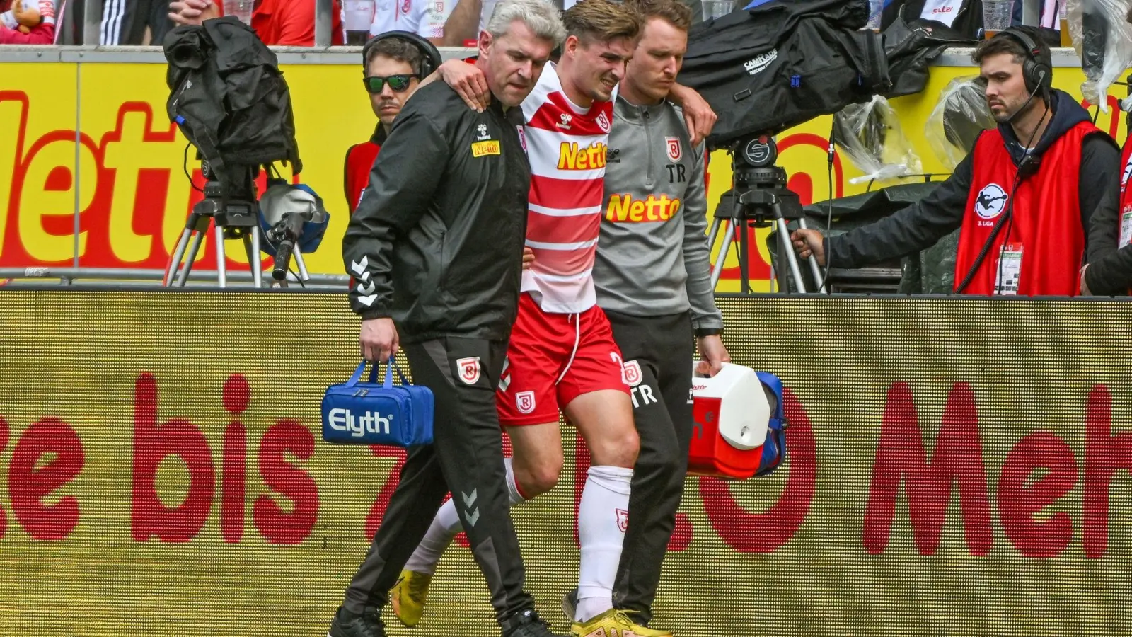 Elias Huth (M) von Regensburg wird verletzt vom Platz geführt. (Bild: Armin Weigel/dpa)