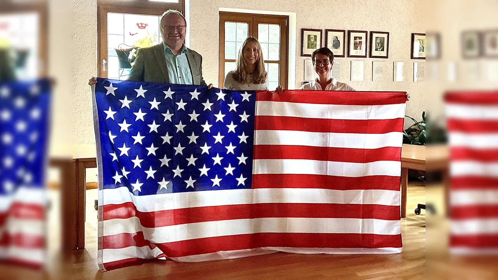Die Juniorbotschafterin Paula Dotzler (Bildmitte) mit Bürgermeister Uwe König und Bundestagsabgeordneter Susanne Hierl zeigen mit der Flagge der USA an, wo es für Paula hingeht (Bild: Gerhard Krones)