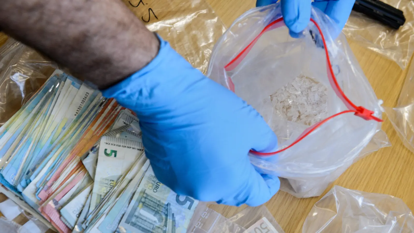 Ein Ermittler präsentiert sichergestelltes Methamphetamin, auch bekannt als Crystal. Vor dem Landgericht Amberg musste sich am Montag ein 23-Jähriger verantworten, weil er mit dieser Droge gedealt haben soll. (Symbolbild: Jens Schlueter /dpa)