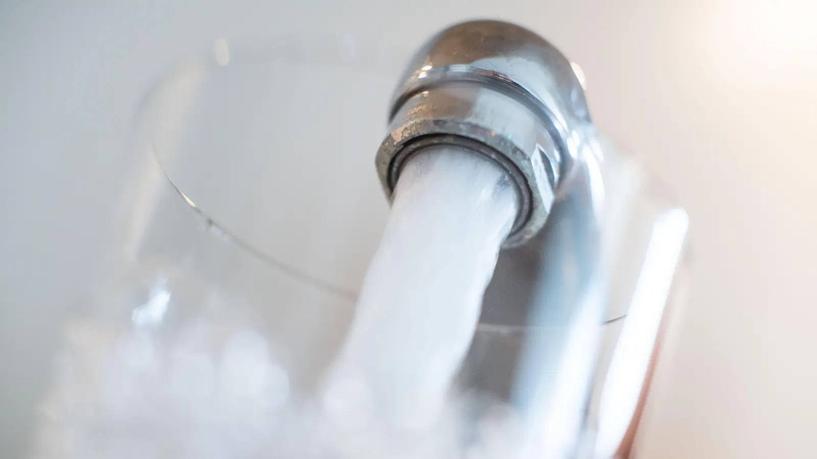 Wasser läuft aus einem Hahn in ein Glas: In einigen Orten im Raum Amberg-Sulzbach wird jetzt das Trinkwasser gechlort. Durch die Überschwemmungen der vergangenen Tage sind Keime in die Wasserversorgung gelangt.  (Symbolbild: Lino Mirgeler/dpa)